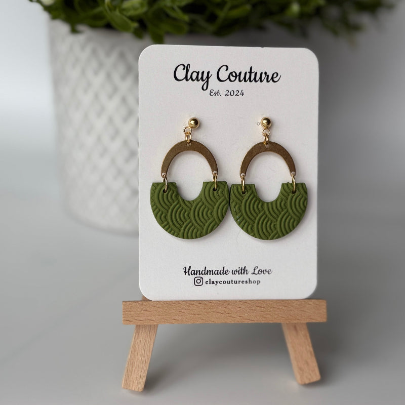 Polymer clay earrings in olive grove color with brass connectors and 18K gold plated studs  on a 'Clay Couture' branded card with a wooden stand