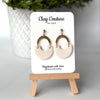 Polymer clay earrings in Irish Creme color with brass connectors and 18K gold plated studs  on a 'Clay Couture' branded card with a wooden stand