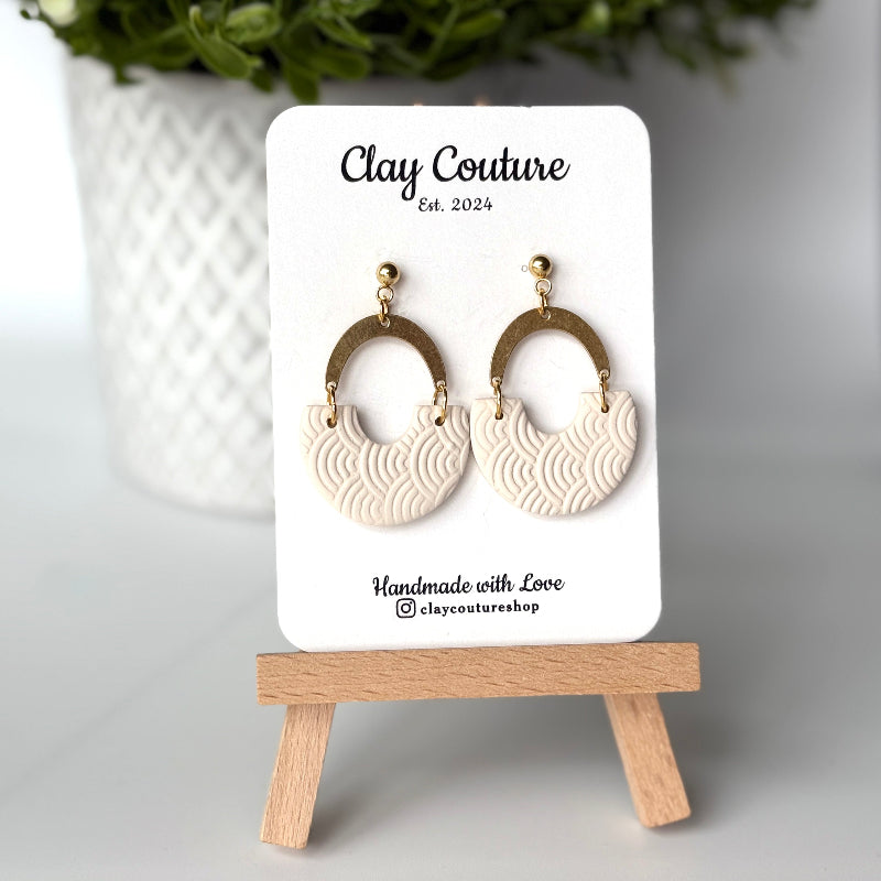 Polymer clay earrings in Irish Creme color with brass connectors and 18K gold plated studs  on a 'Clay Couture' branded card with a wooden stand