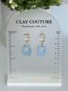 Dusty Blue polymer clay earrings with a crystal stud on a 'Clay Couture' branded size stand