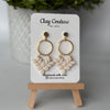 Pair of polymer clay earrings in Irish Creme on Clay Couture branded card on a wooden stand