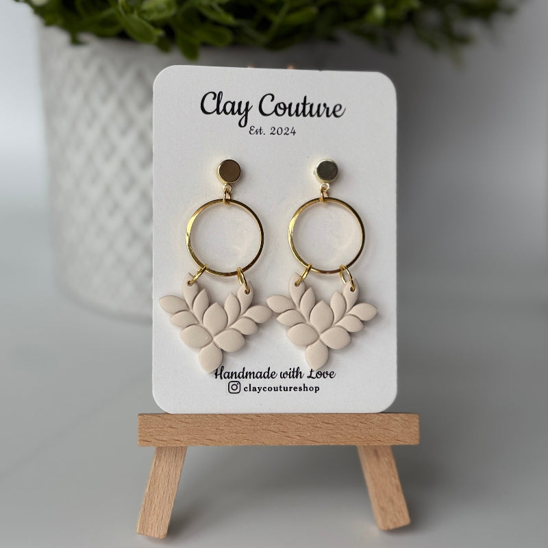 Pair of polymer clay earrings in Irish Creme on Clay Couture branded card on a wooden stand