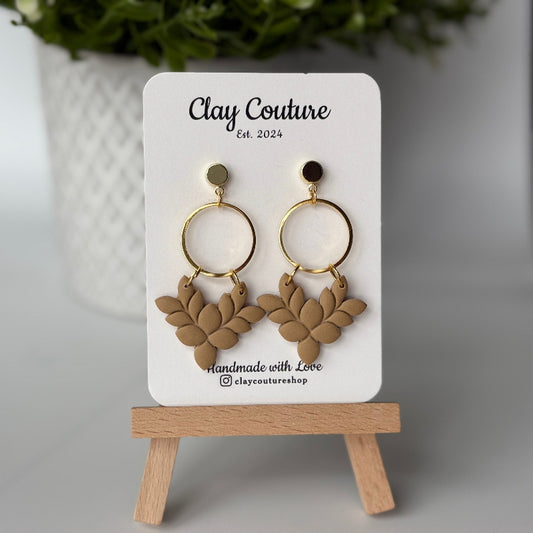Pair of polymer clay earrings in warm sandstone on Clay Couture branded card on a wooden stand