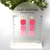 Pink heart-shaped earrings on a Clay Couture size stand