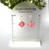 Pair of marbled polymer clay earrings with resin finish  in blush with crystal charm and gold plated studs on Clay Couture branded size stand