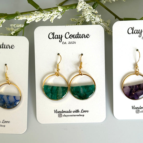 Three pairs of earrings on 'Clay Couture' cards with floral background