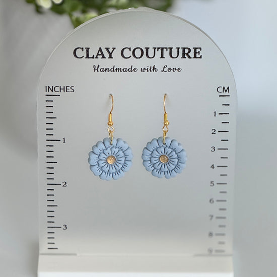Blue flower earrings on a Clay Couture size stand with measurements.