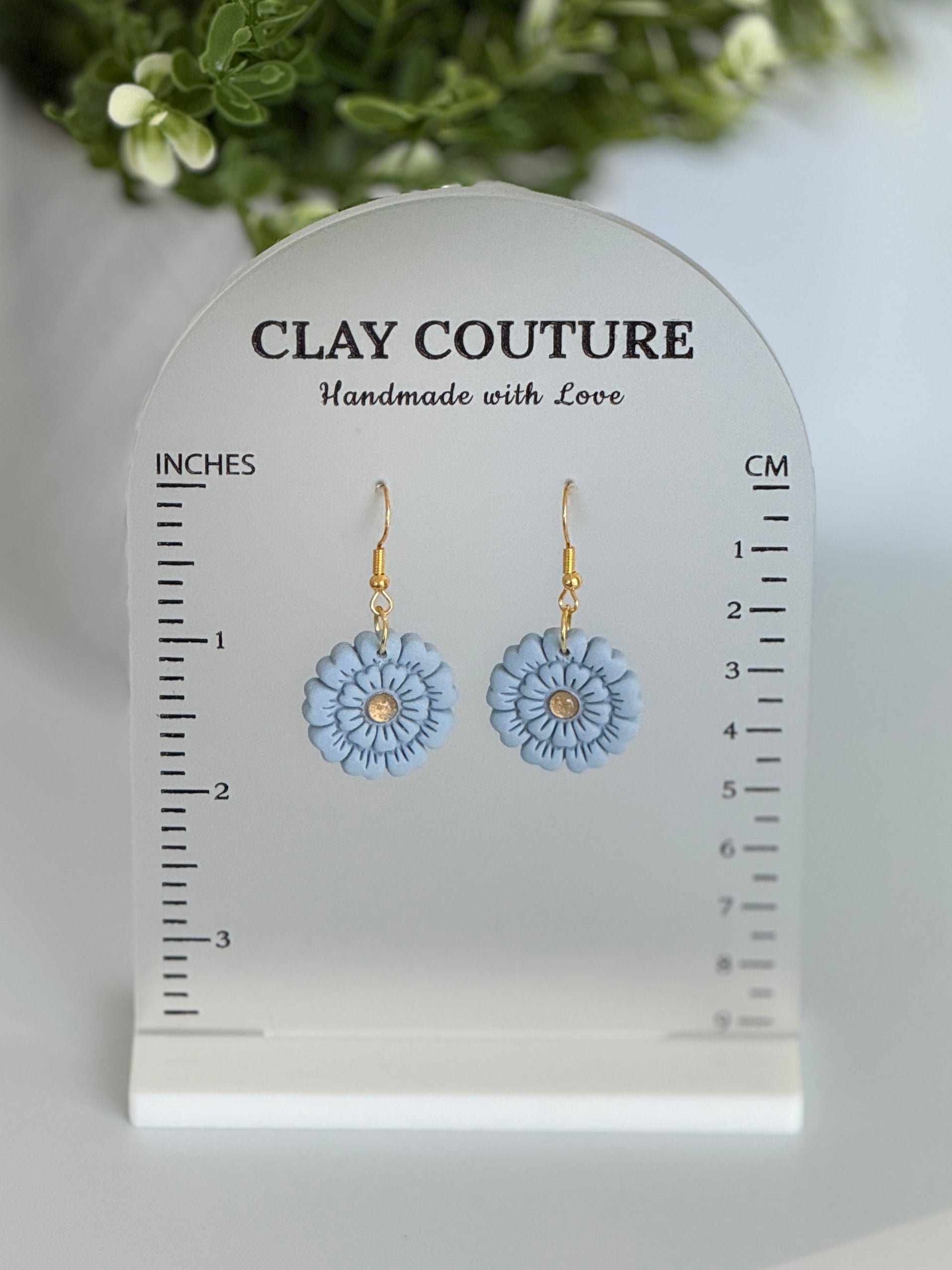 Blue flower earrings on a Clay Couture size stand with measurements.