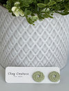 Sage Polymer Clay knot earrings on a Clay Couture card with a potted plant in the background