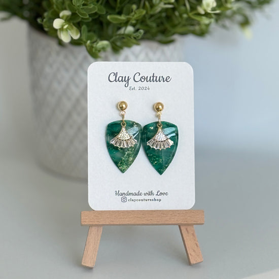 Emerald Green dagger shaped polymer clay  earrings  with a resin finish and gold accents on a Clay Couture branded card.
