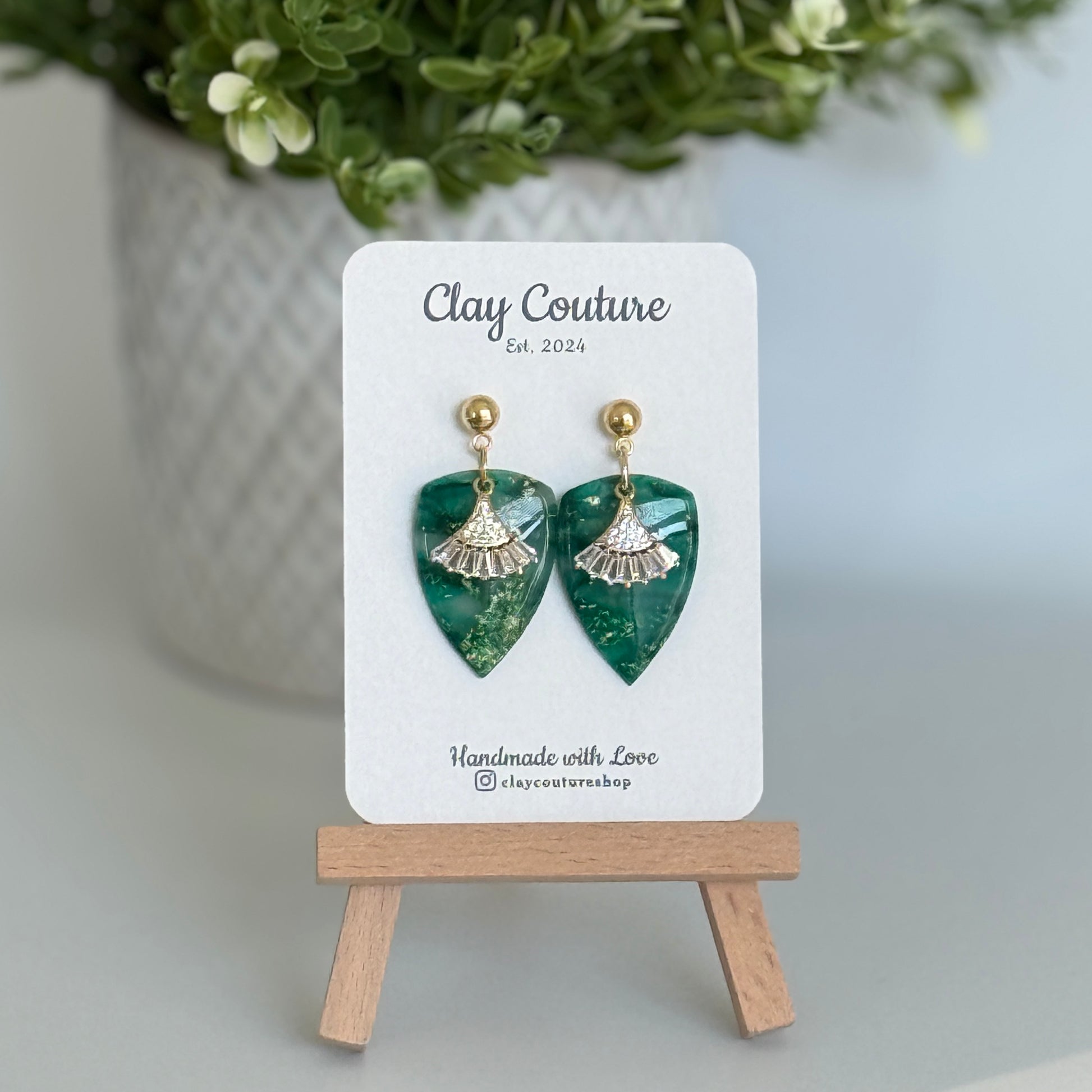 Emerald Green dagger shaped polymer clay  earrings  with a resin finish and gold accents on a Clay Couture branded card.