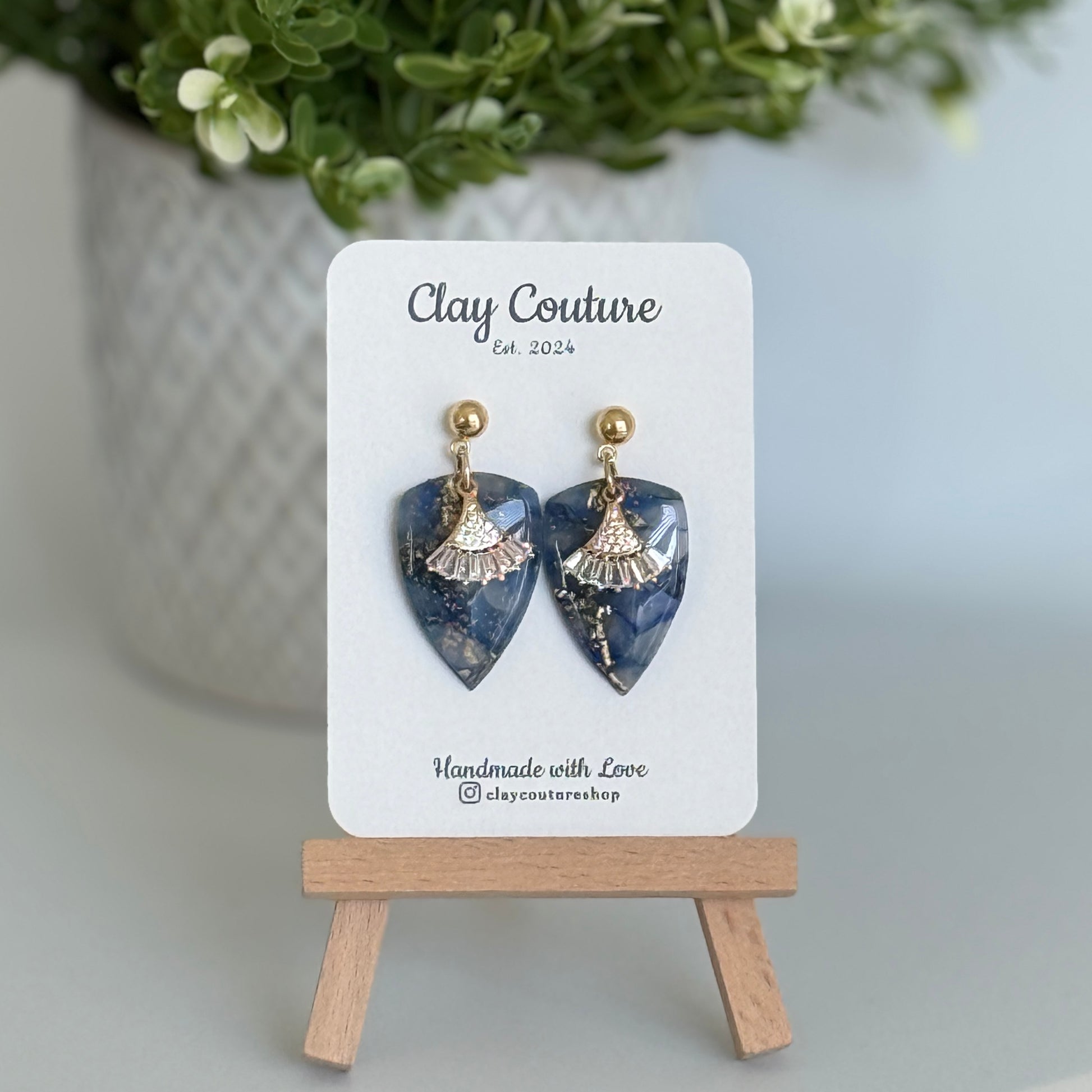 Sapphire Blue dagger shaped polymer clay  earrings  with a resin finish and gold accents on a Clay Couture branded card.