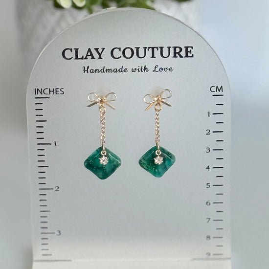Emrald Green Earrings with gold chain and bow on a size stand showing drop length