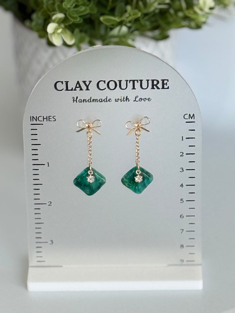 Emrald Green Earrings with gold chain and bow on a size stand showing drop length